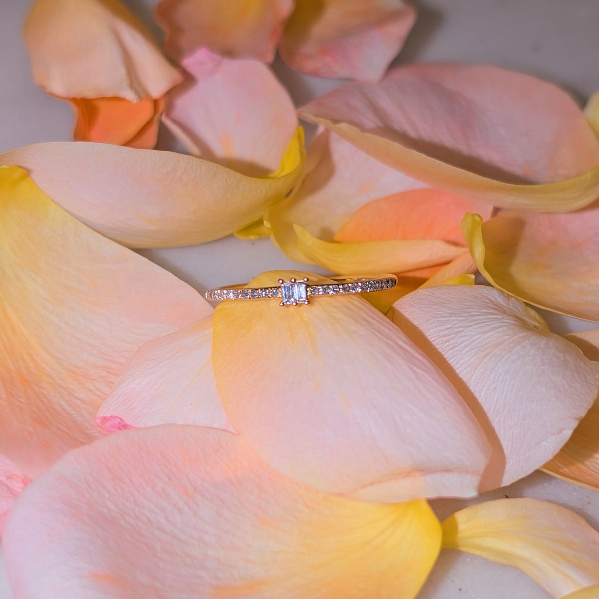Diamond ring on a bed of pink and yellow flower petals